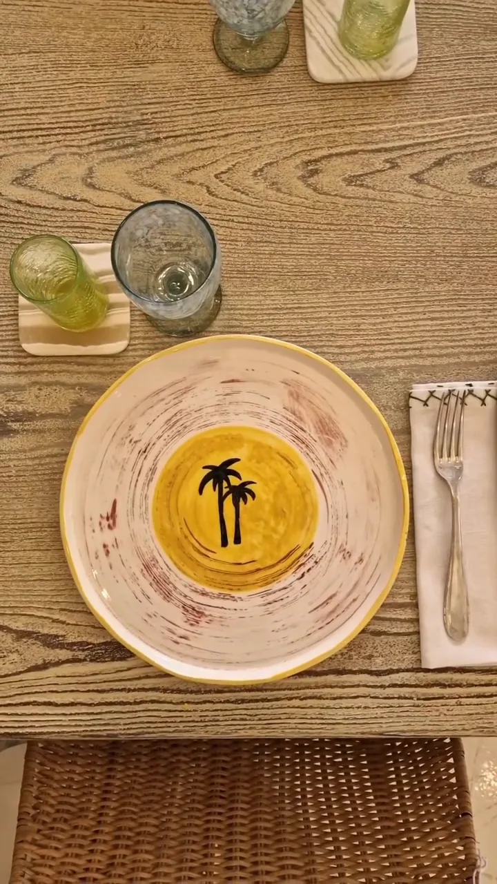 Assiette au palmier noir sur fond moutarde, table dressée